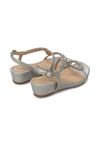 Sandali wedge argentati con finitura testurizzata, cinturini alla caviglia e un accento decorativo di strass nella zona delle dita. Suola piatta.