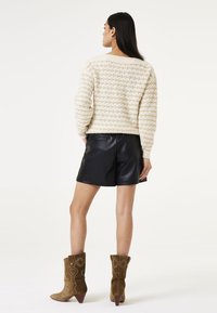 Geweven crèmekleurige trui, zwarte leren shorts en bruine suède cowboylaarzen met bloemenborduursels, met een weergave van de achterkant en de algehele outfitcoördinatie.