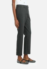 Pantaloni grigi su misura con una texture liscia e taglio dritto, abbinati a ballerine bianco e nere con un motivo a fantasia e doppie cinghie.