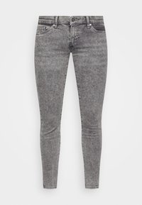 Jeans grigi stretti con una texture lavata, dotati di zip, cinque tasche e dettagli in metallo. Design aderente lungo le gambe.