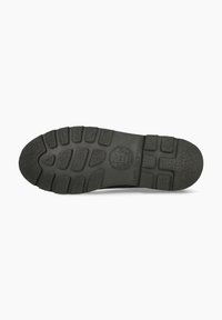 Semelle de chaussure en caoutchouc noir avec surface texturée, présentant de profonds motifs de bande de roulement et un logo central qui indique "Latex 100 % Naturel."
