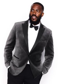 Blazer en velours gris avec revers en satin noir, fermeture à un bouton et deux poches latérales. Assorti à une chemise blanche et un nœud papillon noir.