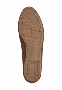 Brown shoe sole with textured rubber, featuring a "Soft Flex" label. The design includes grooves and patterns for traction and flexibility.