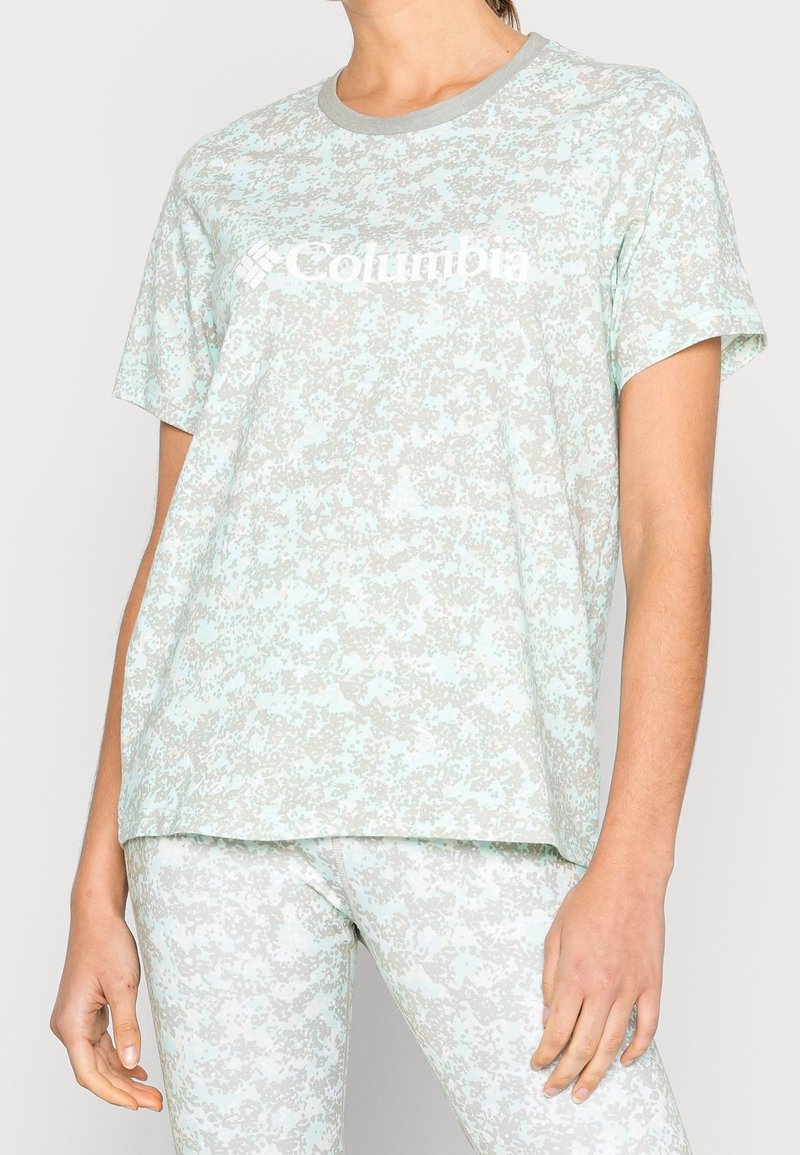 Ljusblå t-shirt med kort ärm och ett prickigt mönster i nyanser av grått, med rund halsringning och Columbia-logotypen i vitt.
