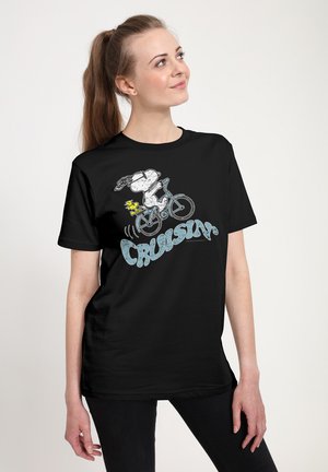 Frau trägt schwarzes T-Shirt mit Snoopy und Woodstock, die Fahrrad fahren, und dem Wort „CRUISIN'“ in hellblauer Schrift.
