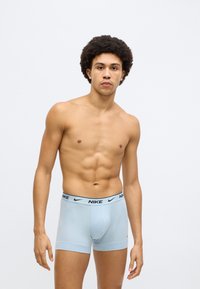 Ανδρικά μπόξερ της Nike σε ανοιχτό μπλε ύφασμα, με μαύρη ελαστική ζώνη μέσης που φέρει το λογότυπο Nike, εφαρμοστή σχεδίαση με δίχως ραφές εμπρόσθια επιφάνεια.