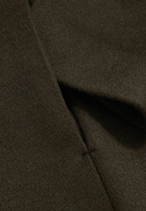 Tissu en laine vert foncé, présentant une texture douce avec une finition tissée et un détail de couture visible. Le design est lisse et sans couture.