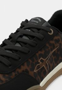 Baskets noires et marron avec un design à imprimé léopard, tissu texturé, lacets noirs et une semelle en caoutchouc beige avec un détail de logo.