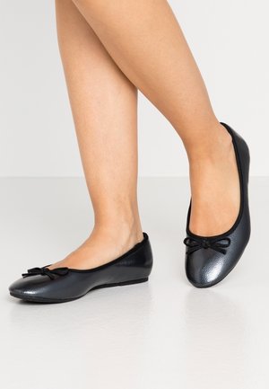 Black ballet flats made of textured leather, featuring a round toe and a small bow detail on the front, with a low, flexible sole.
