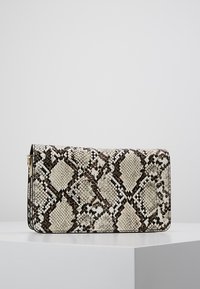 Borsa a mano realizzata in ecopelle di serpente, con un motivo a diamante in crema e marrone, dalla superficie liscia e con rifiniture nere.