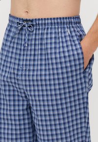 Boxer da uomo a quadri blu e bianchi con vita elastica, dettaglio con coulisse e tasche laterali. Tessuto leggero, design casual.