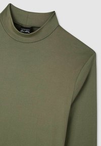 Oliwkowa bluzka z długim rękawem i wysokim kołnierzem, wykonana z gładkiego materiału, o dopasowanym kroju. Charakteryzuje się minimalną liczbą szwów i brakiem widocznych elementów metalowych.