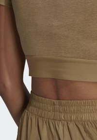 Cropped brown fabric top with a soft texture, featuring a fitted waistband. Paired with lightweight, elastic waistband, gathered skirt in a matching tone.