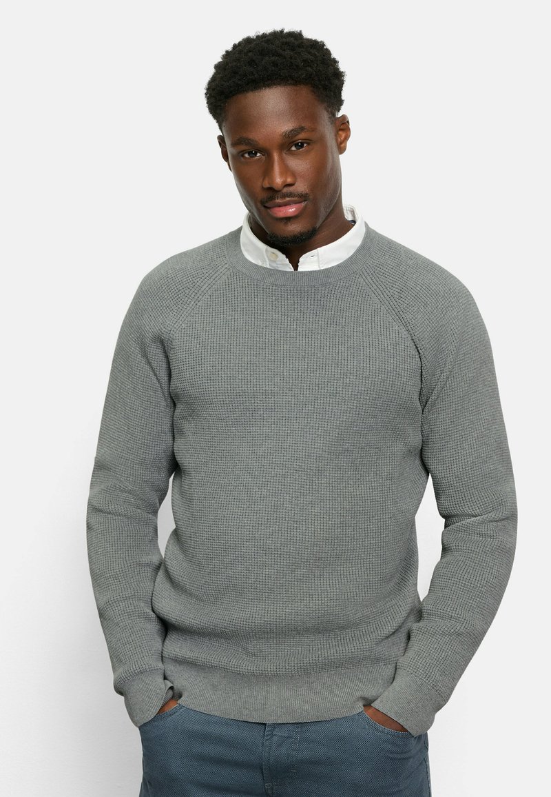 Helles graues, strukturiertes Sweatshirt mit gerippten Bündchen und Saum, getragen über einem weißen Hemd mit Kragen. Gerade geschnitten mit lockerer Passform und Rundhalsausschnitt.