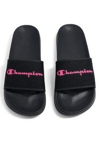 Chanclas negras con tira texturizada y diseño de ventilación, con el logotipo "Champion" en letras rosas.