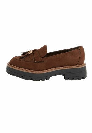 Brun ruskind loafers med kvaster, tyk tan-lægning og kraftig sort rillesål vist fra siden.