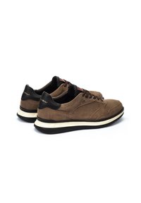 Zapatillas de gamuza marrón con acentos de cuero negro, con cordones redondos y una entresuela blanca. El diseño incluye detalles de costura sutiles.