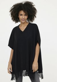 Schwarzer Poncho mit V-Ausschnitt, weiten Ärmeln und fransigem Saum. Hergestellt aus weichem Material mit glatter Textur.