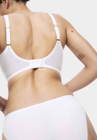Witte beha met verstelbare banden, haak-en-oogsluiting, een gladde textuur en minimale ontwerpdetails. Witte slip met eenvoudige snit en stof.