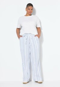 Weißes kurzärmliges Hemd, lässiger Schnitt. Leichte Stoffhose mit blauen und weißen Streifen, Bindegürtel, weitem Bein und zwei seitlichen Taschen.
