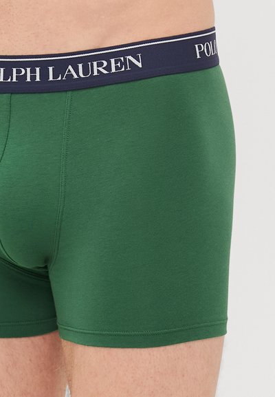 Zeleni bokserice iz mehkega materiala, z mornarsko modrim pasom in belim logotipom "Polo Ralph Lauren" ter šiviljskim detajlom.