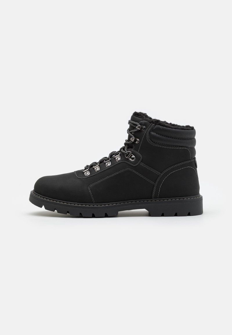 Botte d'hiver en cuir noir avec cheville rembourrée, œillets métalliques, doublure en fourrure, semelle en caoutchouc épaisse et semelle crantée, vue de côté.