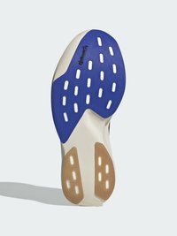 Semelle d'une sneaker avec une section en caoutchouc bleu, une semelle intermédiaire blanche et des motifs de grip texturés; comprend des accents marron clair et des trous de drainage.