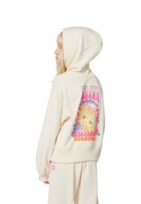Cremfarbener Hoodie aus weichem Material mit einem bunten Sonnen- und Blumen-Design auf der Rückseite, mit gerippten Bündchen und Saum.