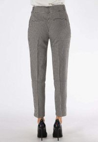 Pantaloni a vita alta a scacchi in bianco e nero, con una vestibilità slim, tasche frontali e tasche a filetto posteriori, abbinati a tacchi neri.