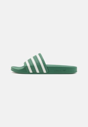 Sandale slide verte Adidas avec trois bandes blanches sur la bride et une semelle texturée, vue de côté sur un fond uni.