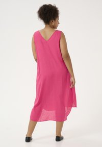 Vestido sin mangas rosa con escote en V, hecho de una tela ligera. Presenta un corte holgado y aberturas laterales, lo que proporciona comodidad y libertad de movimiento.