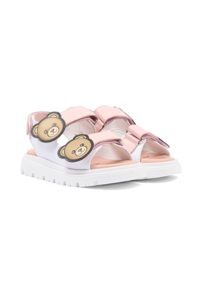 Różowo-białe sandały dziecięce z masywnymi białymi podeszwami i naszywkami w kształcie twarzy misia na paskach, pokazane obok siebie na białym tle.