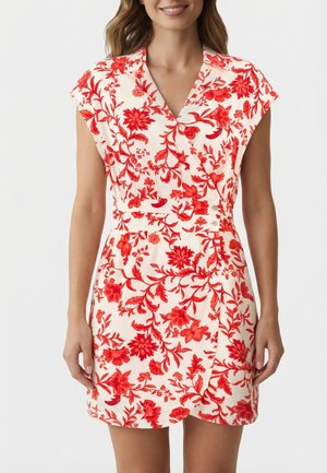 Mujer con vestido blanco de mangas cortas y un estampado floral rojo, con escote en V y cintura estilo envolvente.