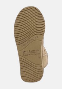 Suela de goma marrón con un patrón de ondulación, etiquetas grabadas "Resistente al Agua" y "EMU Australia", indicando calzado fabricado en Australia.