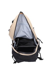 Zwarte en beige rugzak met een ruime binnenkant. De voering is lichtblauw en heeft een ritsvak en mesh-vakken aan de zijkanten.
