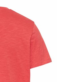 Kortærmet t-shirt i heather koralfarvet, lavet af blødt stof med en let struktureret overflade. Rund hals med standard syninger.