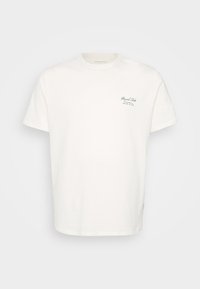 Hvid bomuld t-shirt med korte ærmer, rund hals og et lille grønt trykt logo på venstre bryst. Enkel, lige pasform.