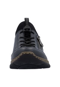 Chaussure en cuir noir avec une surface texturée, dotée de lacets, d'un détail zippé et d'une semelle en caoutchouc. Surpiqûre autour de la base.