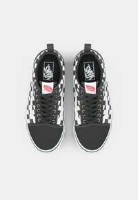 Mustavalkoiset ruudulliset kangastossut, joissa on musta kärki, valkoiset nauhat ja Vans-logo kengän kielellä. Mallissa on matala design.