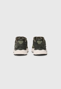 Green mesh athletic shoes with textured overlays, a thick white midsole, and a black rubber outsole, featuring a padded collar and tongue.
