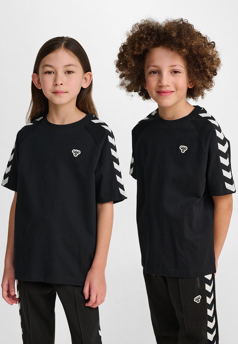 T-shirt in cotone nero a maniche corte, con motivi a zig-zag bianchi sulle spalle e un piccolo logo sul petto. Vestibilità casual.