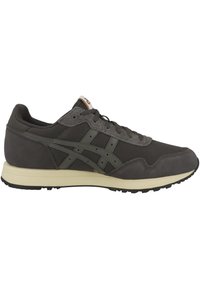 Zapatillas gris oscuro con materiales de malla y ante, que presentan una entresuela gris clara y acentos verdes texturizados. Diseño atlético clásico.