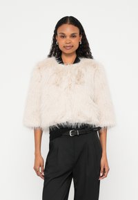 Valepalitus lühike jakk helebeeži toonis, millel on ümmargune kaelus ja kolmveerandvarrukad. Tekstuurilt pehme ja kohev, loodud kihiliseks kandmiseks.