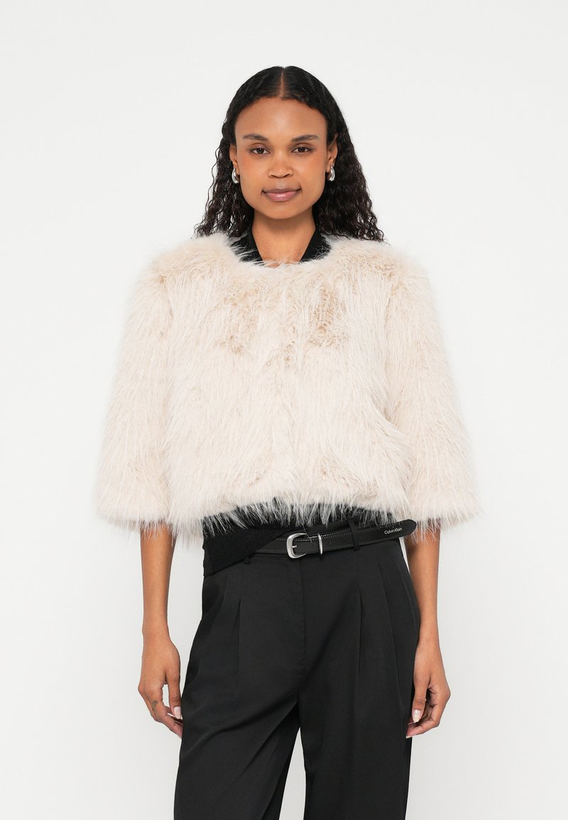 Valepalitus lühike jakk helebeeži toonis, millel on ümmargune kaelus ja kolmveerandvarrukad. Tekstuurilt pehme ja kohev, loodud kihiliseks kandmiseks.