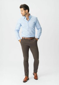 Světle modrá košilová košile, hnědé slim-fit kalhoty a hnědé formální boty. Obsahuje opasek a hodinky, s viditelnou strukturou látky.