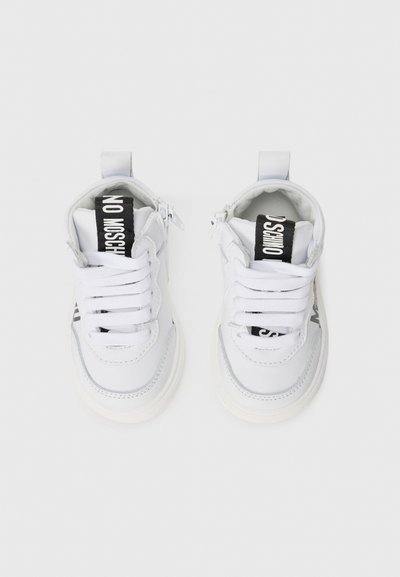 Witte sneakers met een gladde leren afwerking, voorzien van platte witte veters, een zwart merklabel op de tong en een dikke witte rubberen zool.