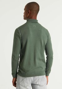 Grüner Langarmpullover mit hohem Kragen und gerippten Bündchen, der eine glatte Textur und minimale Nahtdetails auf der Rückseite aufweist.
