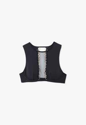 Black sports bra featuring a mesh panel at the front, adorned with circular gold accents along the closure, and wide straps for support.