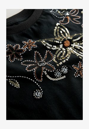 Tricou negru cu modele florale brodate în fire de aur, maro și paiete argintii, cu cusături intricate și detalii texturate.