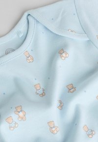 Lyseblåt stof med et gentaget mønster af små bamser i stribede og butterfly-accenter. Blød tekstur med subtile stjernedetaljer.